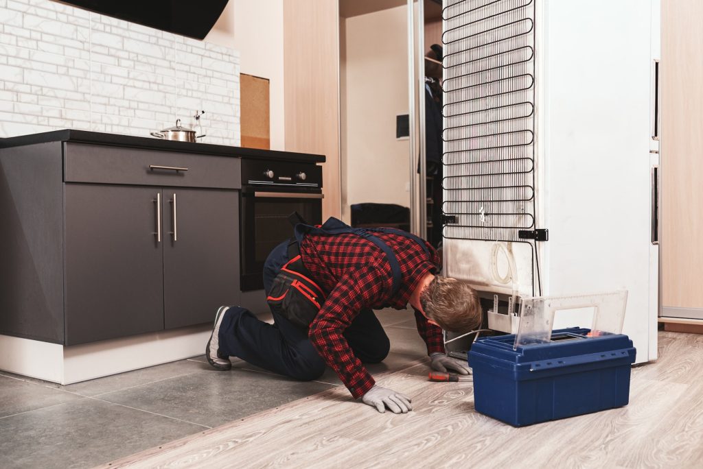 Ups, You have a trouble. Young Male Technician Checking Refrigerator